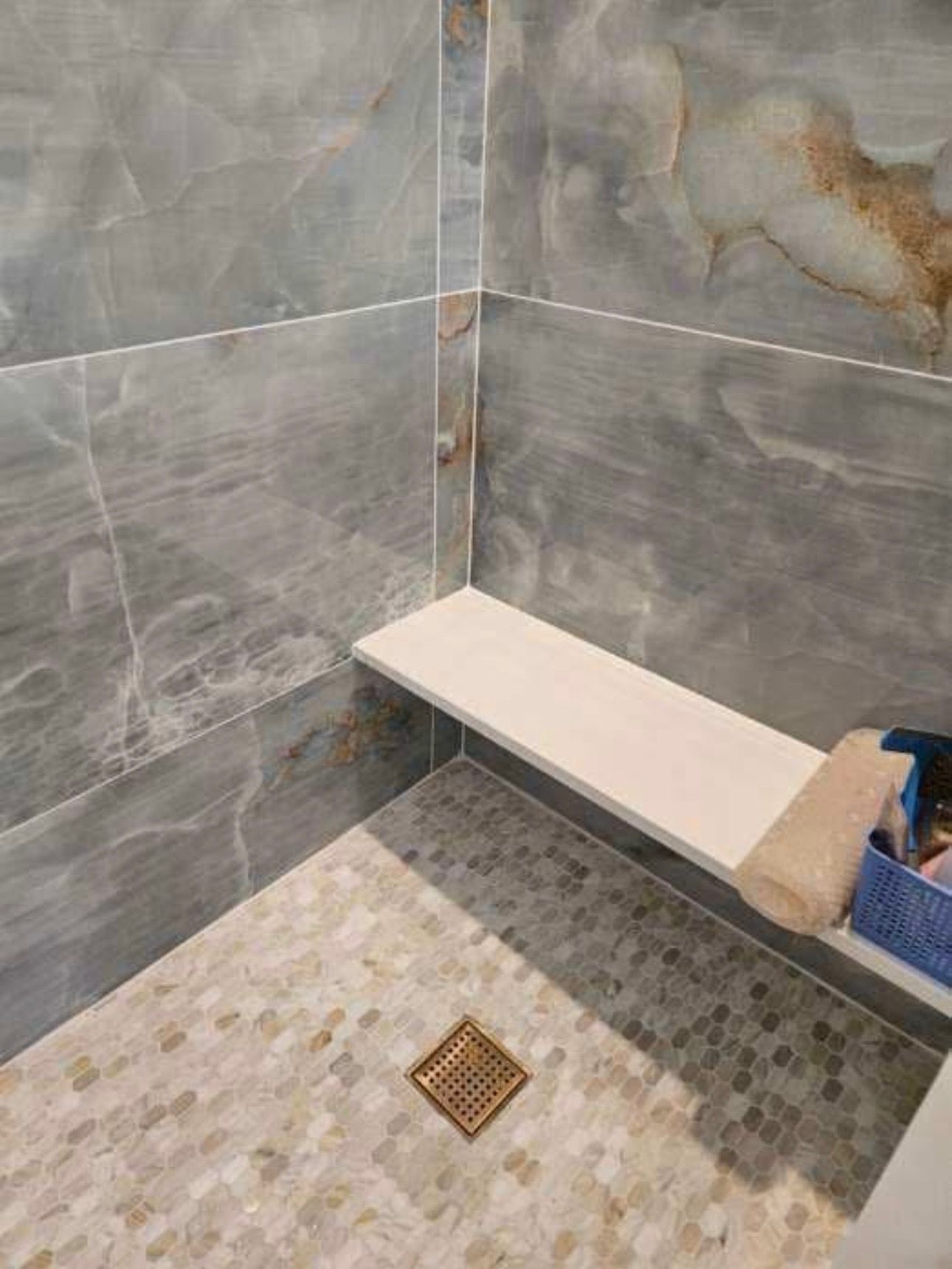 A bathroom with a walk in shower and a bench.