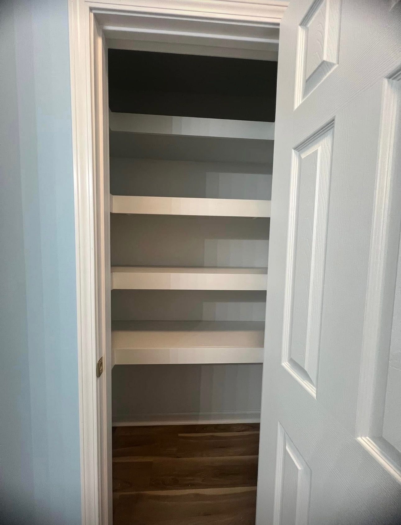 A closet with a door open and shelves in it.