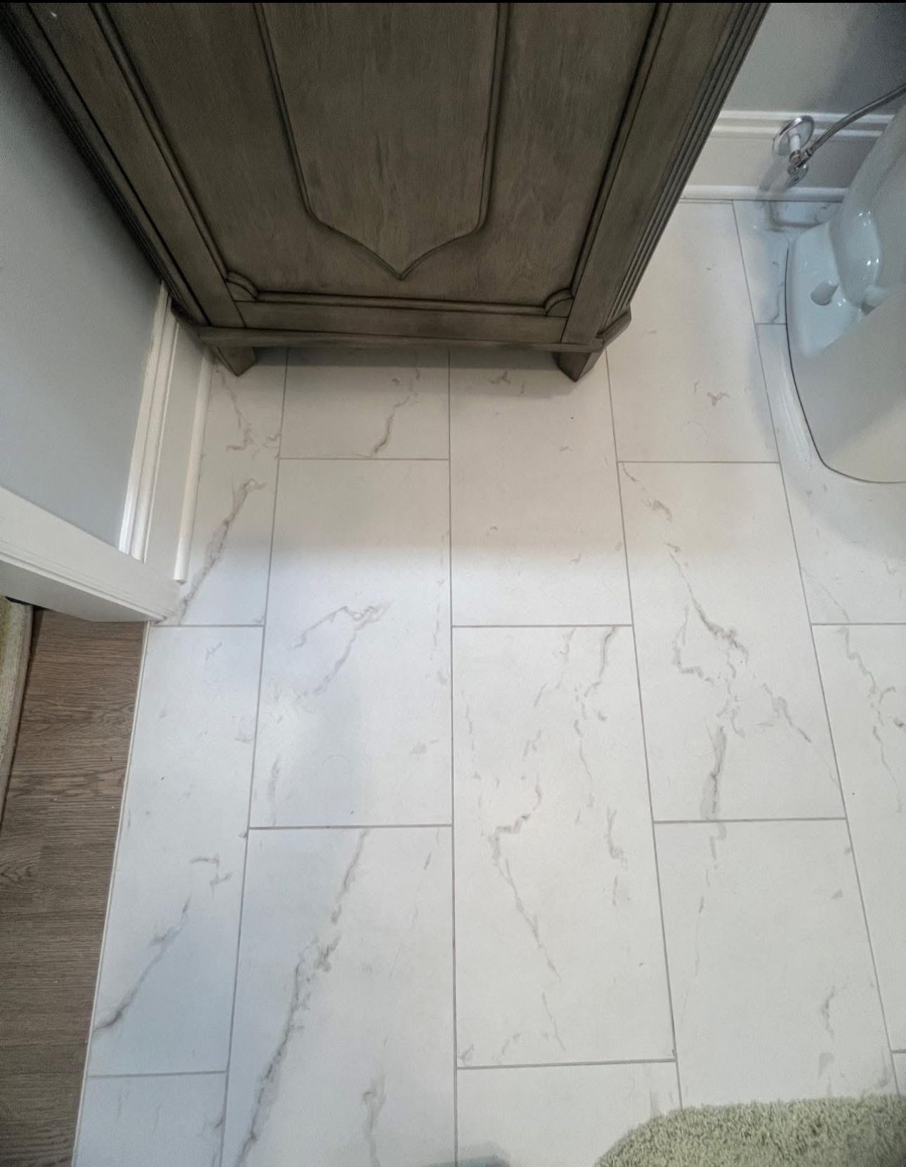 A bathroom with a marble floor and a wooden cabinet.