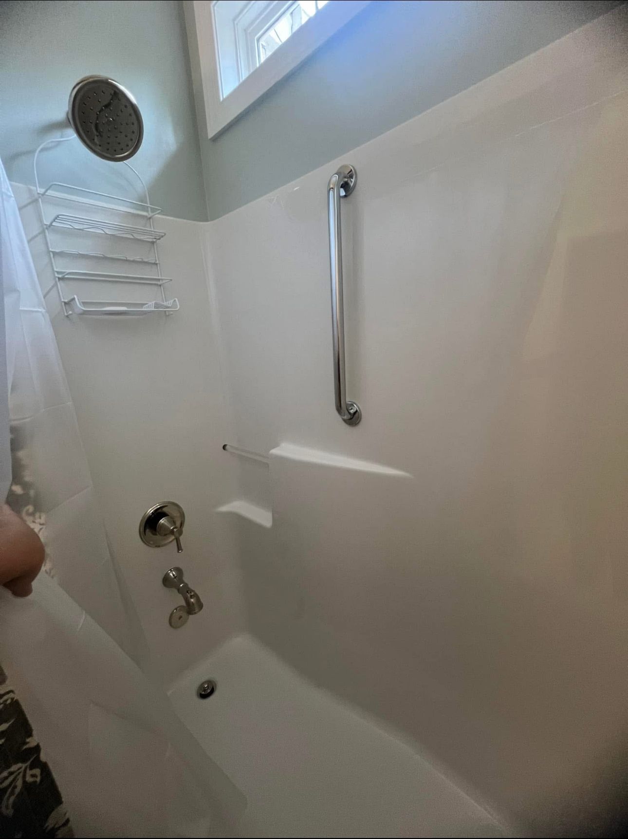 A person is standing in a bathroom with a bathtub and shower.