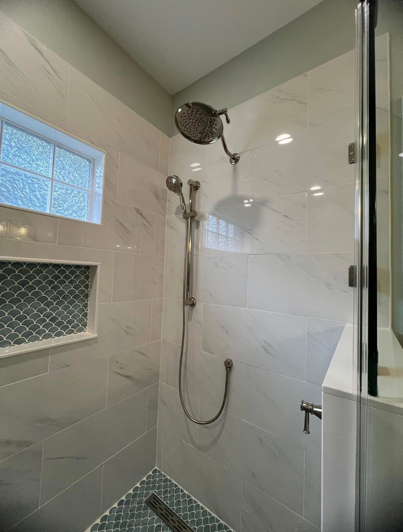 A shower with a glass door and a shower head.