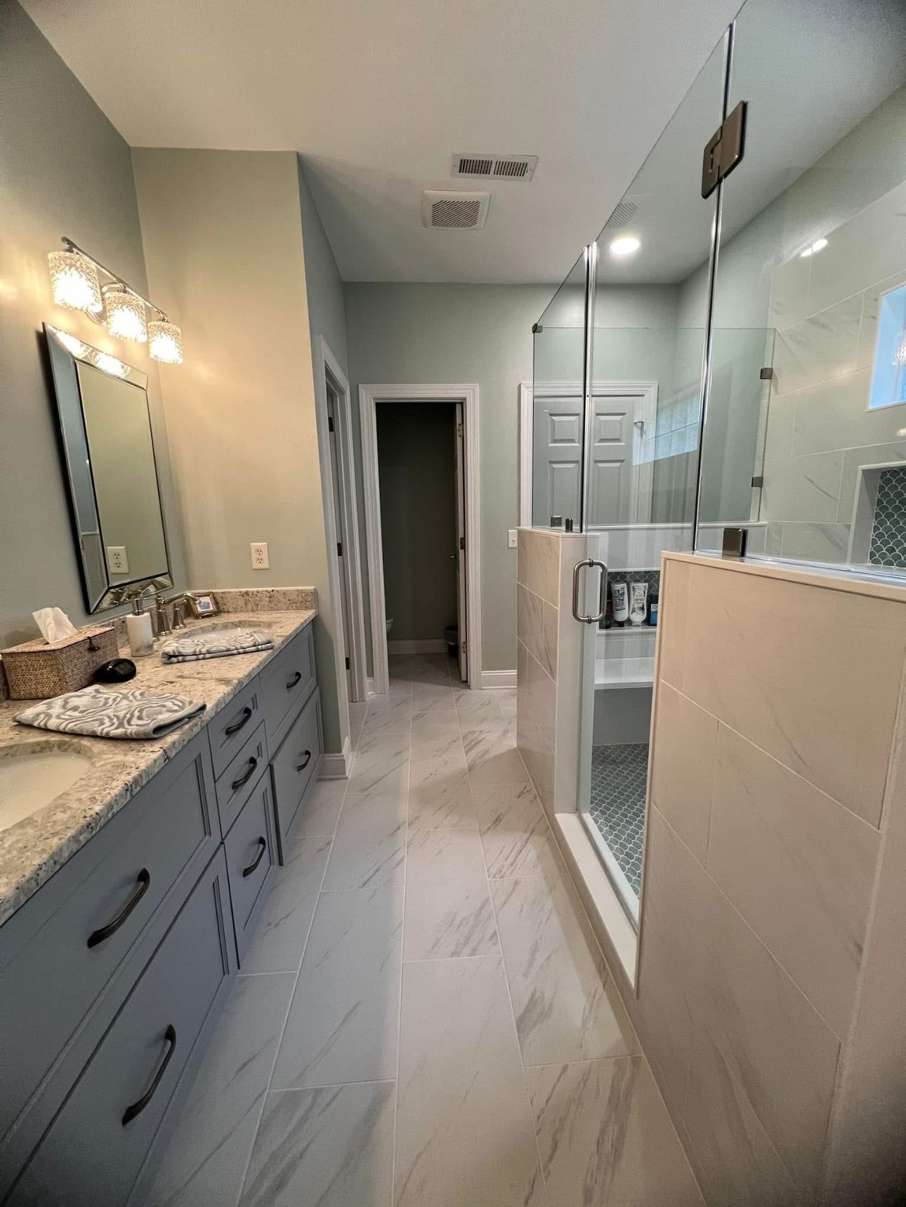 A bathroom with two sinks and a walk in shower.