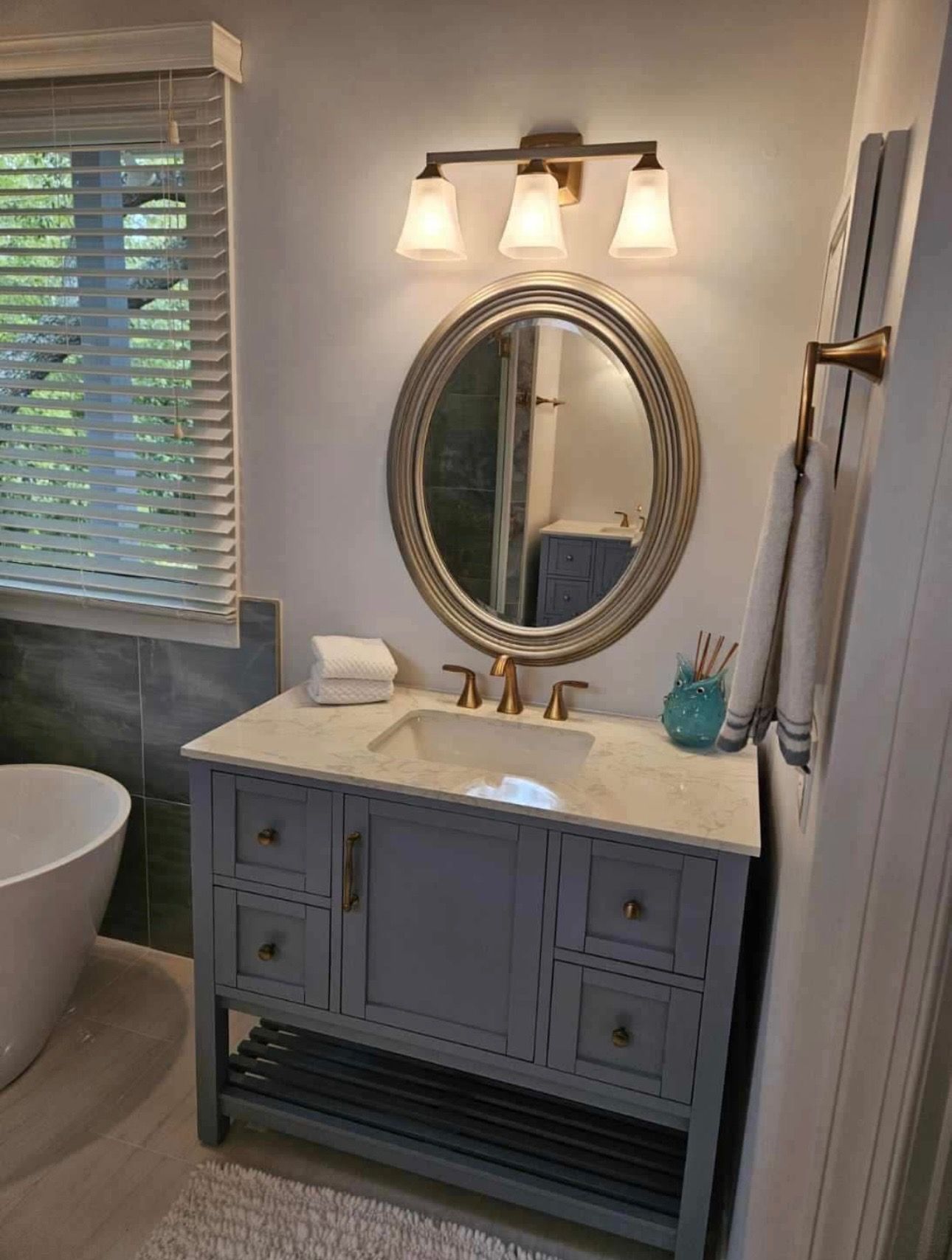 A bathroom with a sink, mirror, and bathtub.
