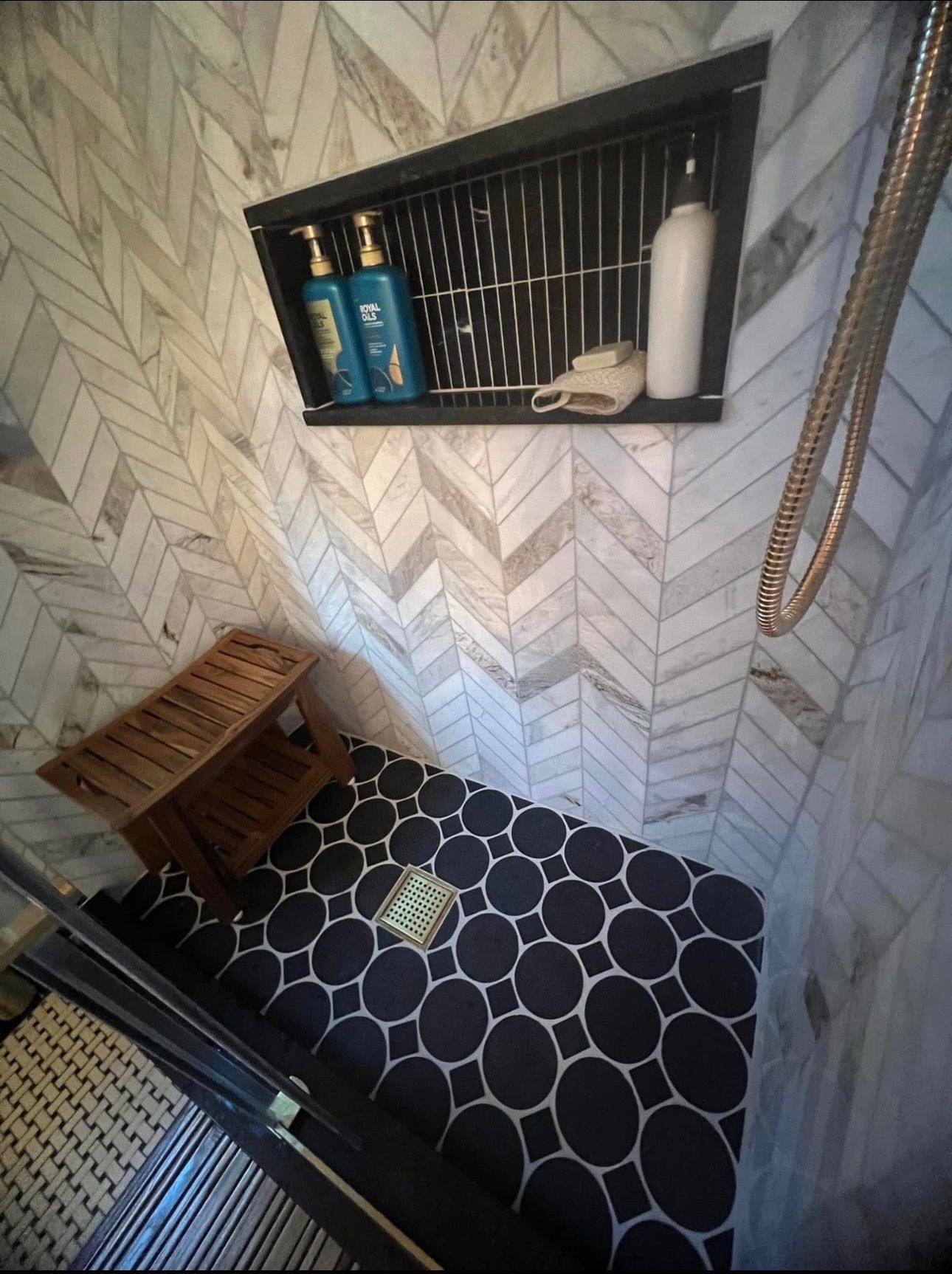 A bathroom with a shower and a shelf with shampoo bottles on it