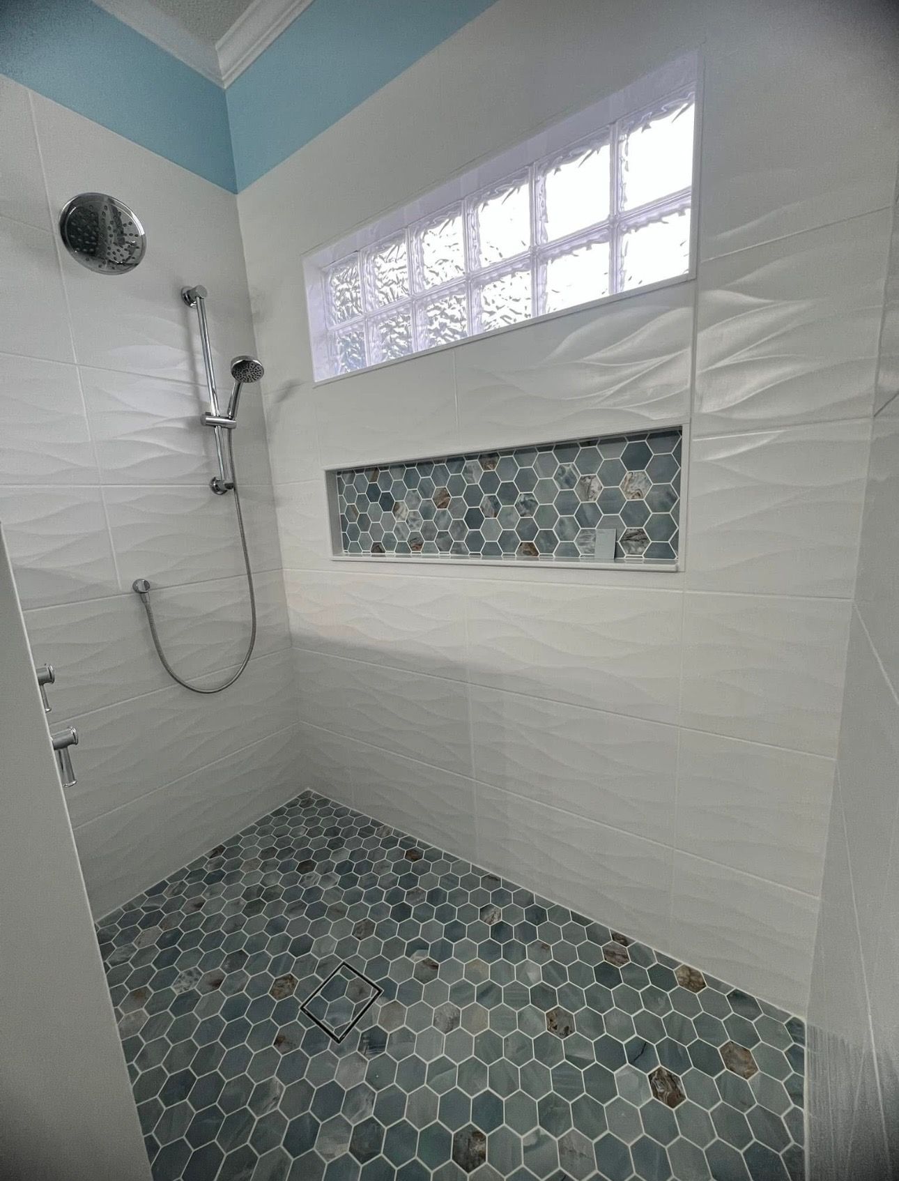 A bathroom with a walk in shower and a window.