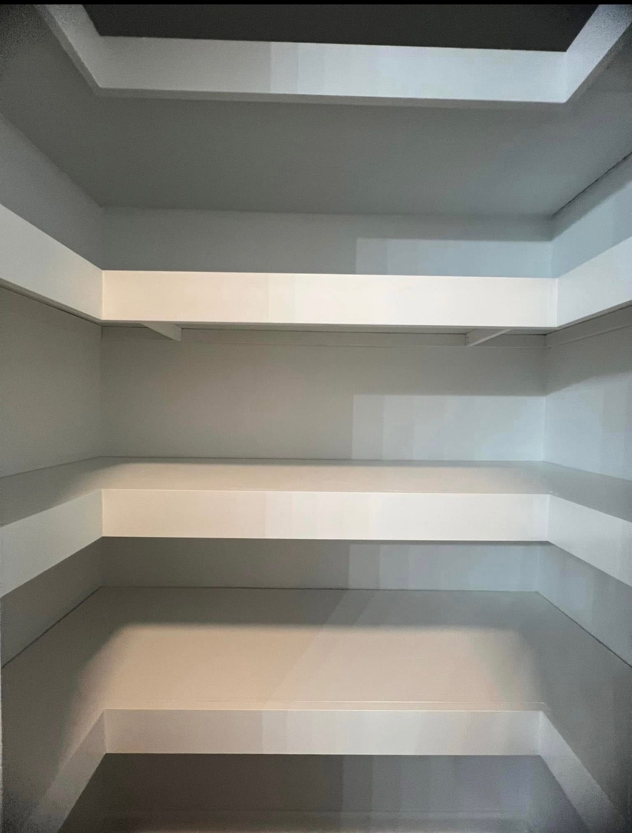 There are three shelves in the corner of a room.