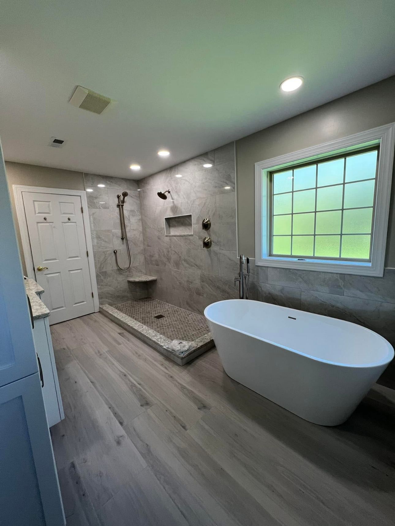 A nice-looking bathroom with a tub, shower, and window.