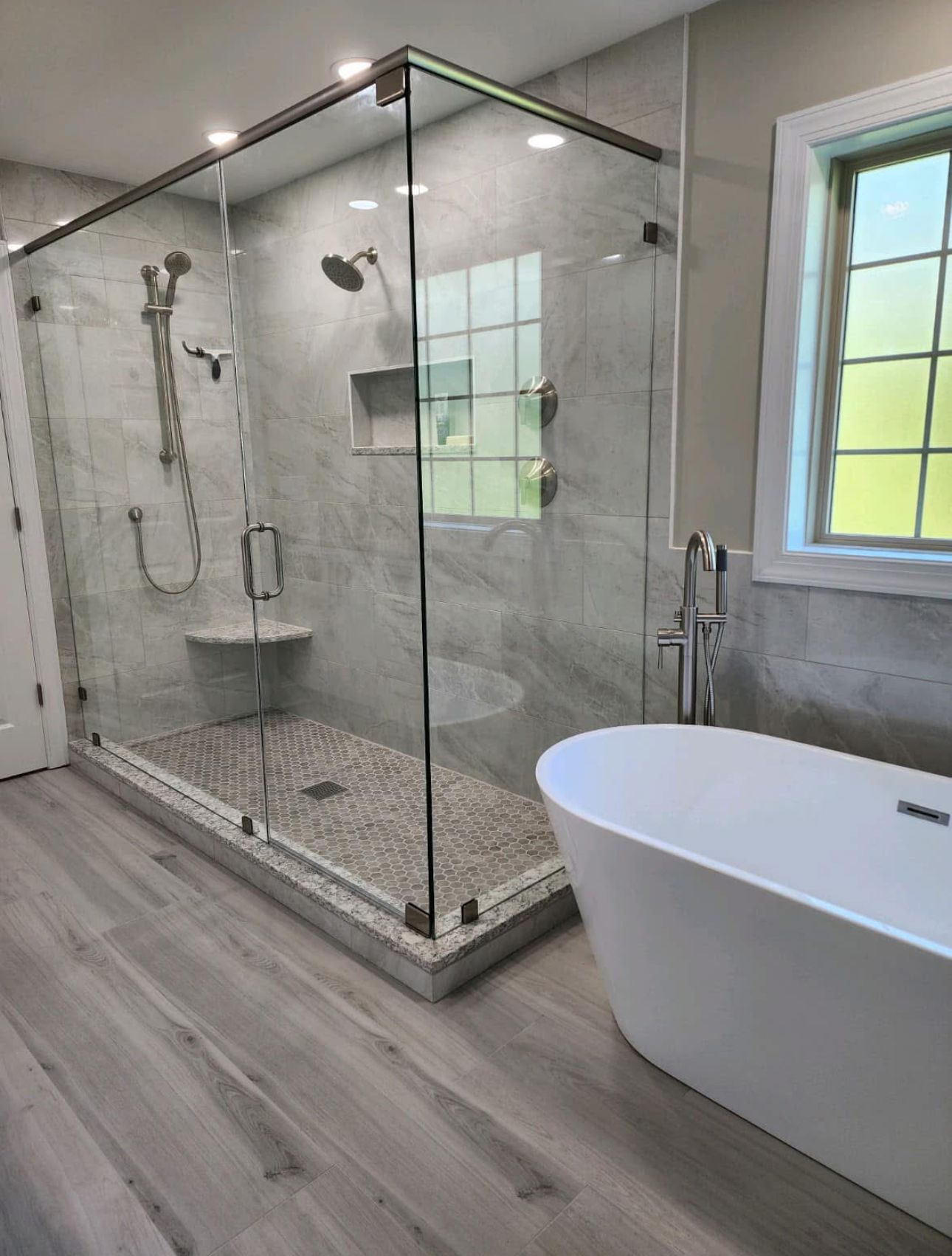 A nice-looking bathroom with a tub, shower, and window.