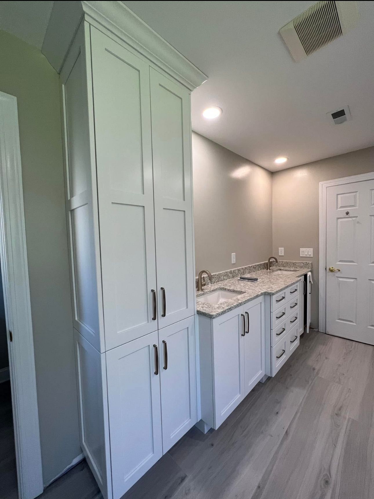 A bathroom with white cabinets and granite counter tops.