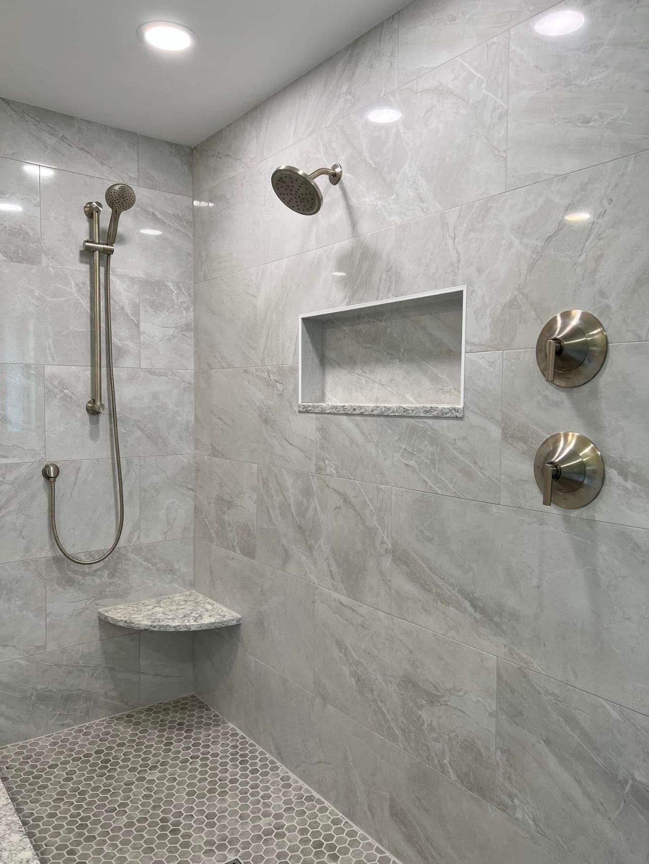 There is a shower with a bench and a shower head.