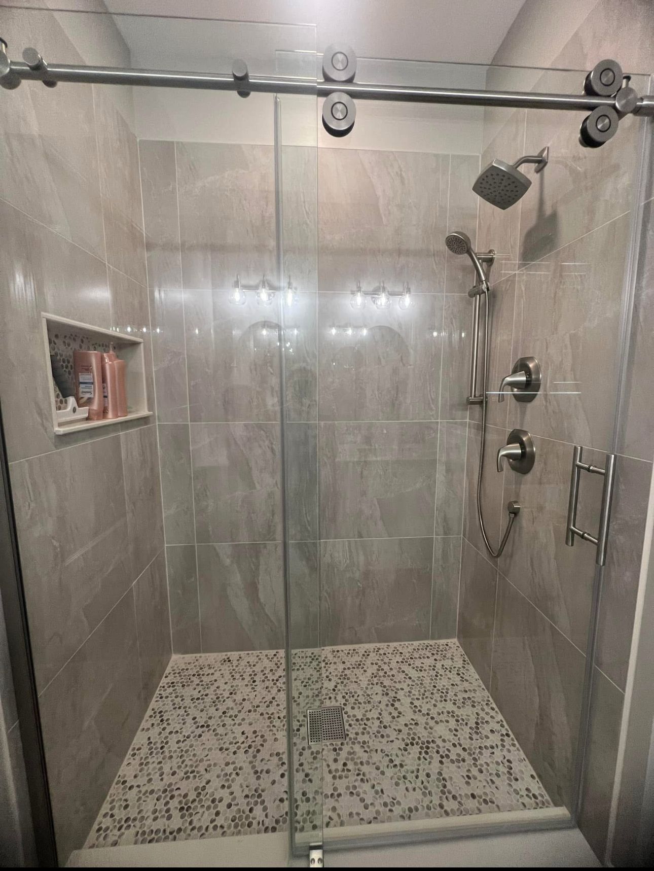 A shower with a sliding glass door and a shower head.