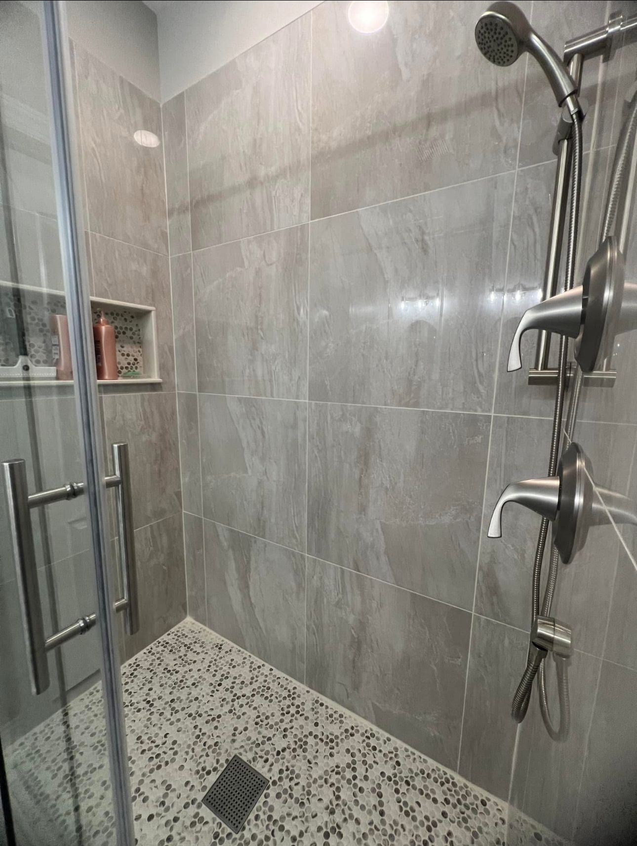 A walk in shower with a glass door and a shower head.