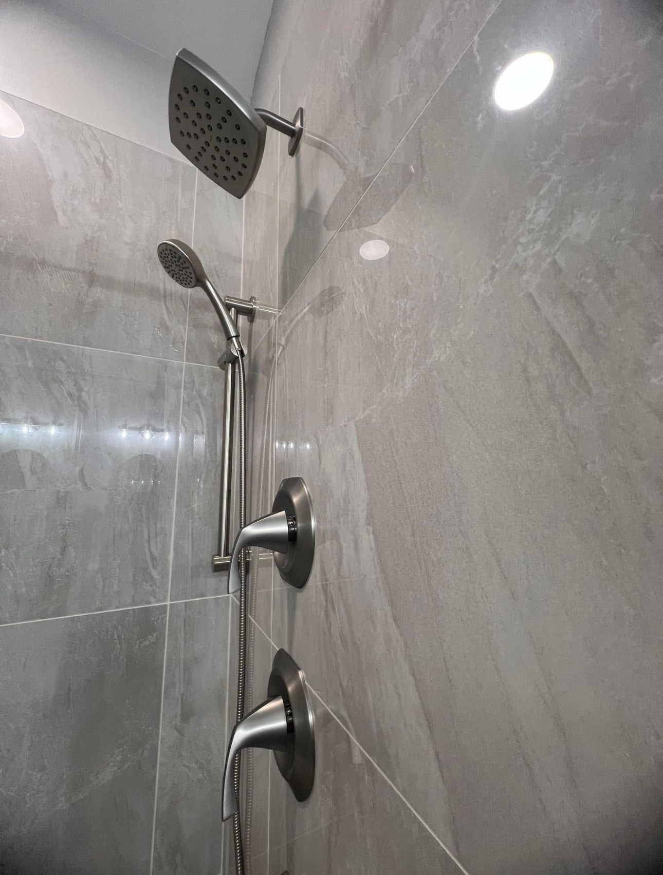 A shower head is hanging on a tiled wall in a bathroom.