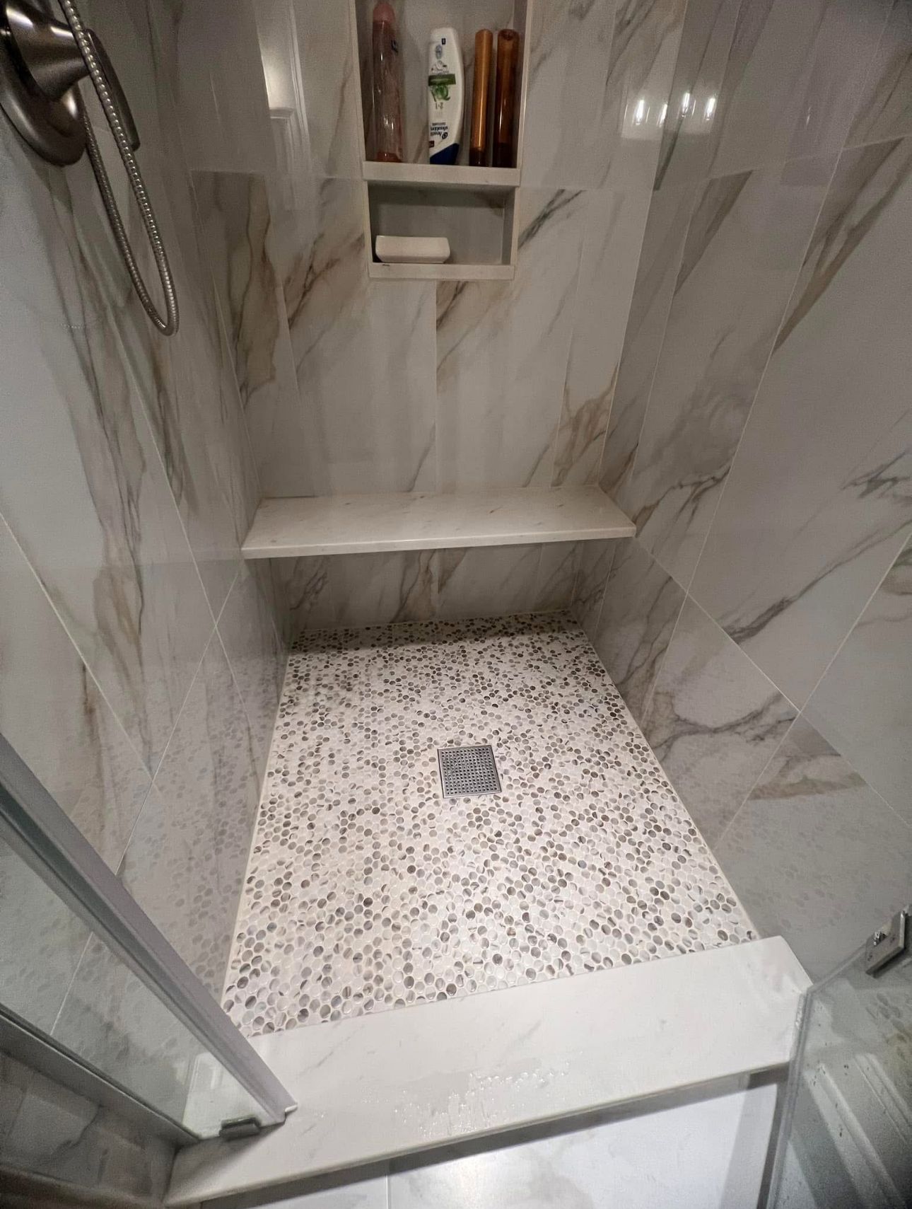 A shower stall with a tiled floor and a shower head.