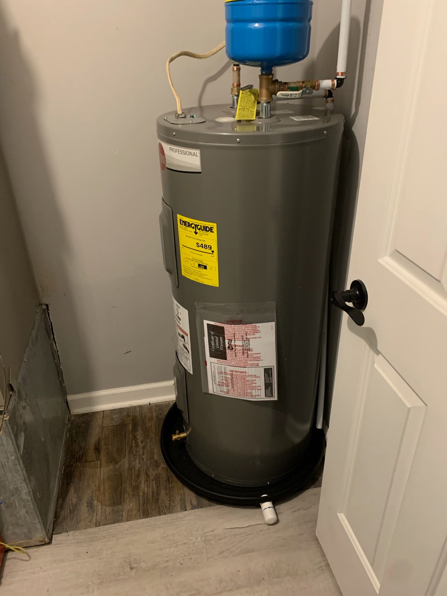 A water heater is sitting in a room next to a door.