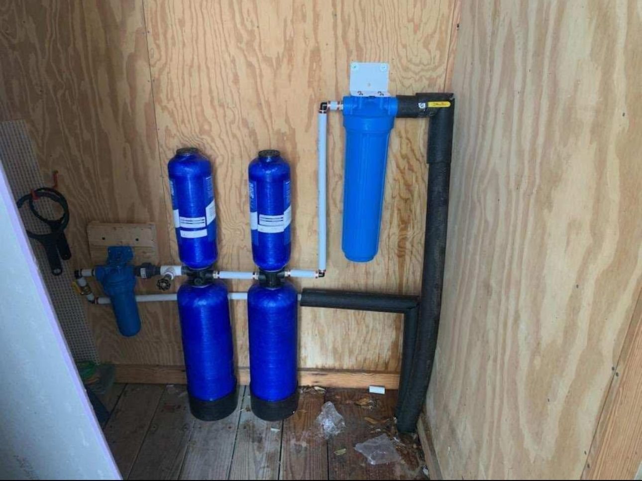 Three blue water filters are installed in a wooden room.