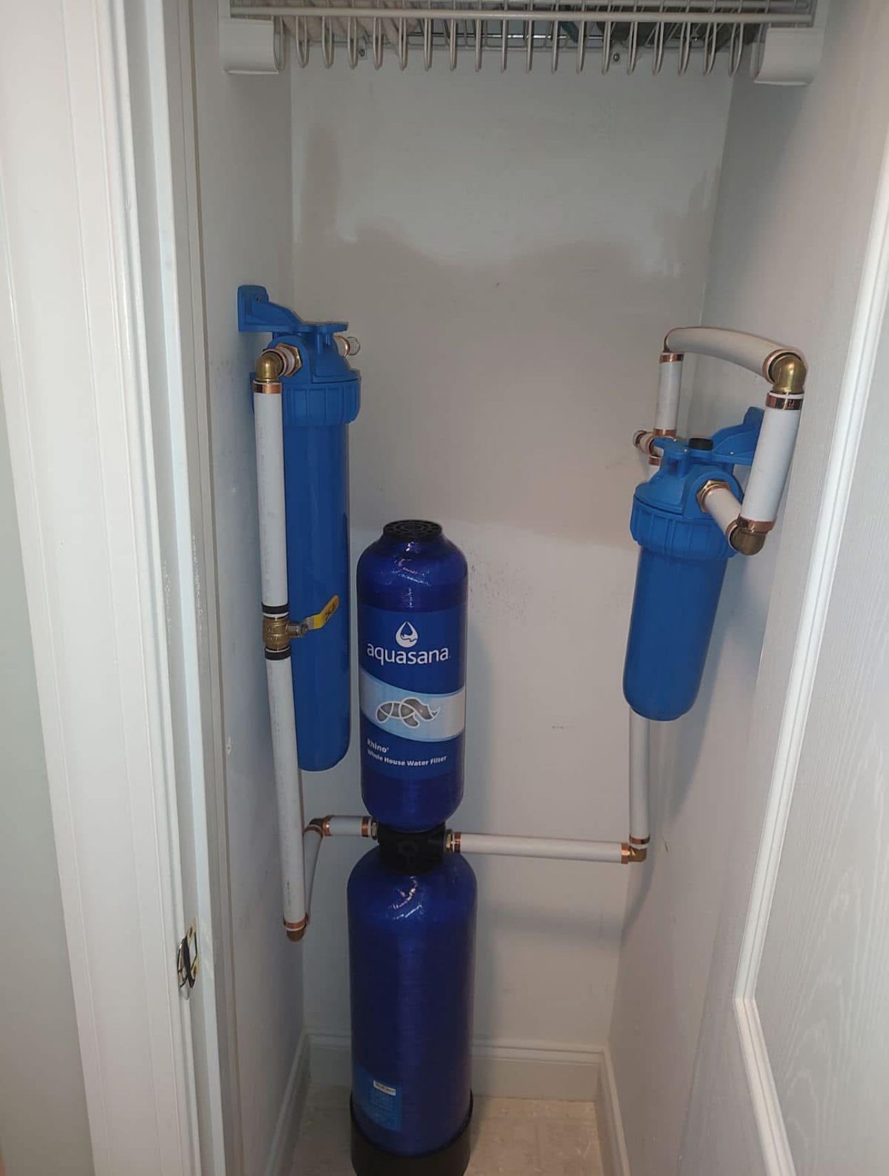 A blue water filter is sitting in a closet next to a door.