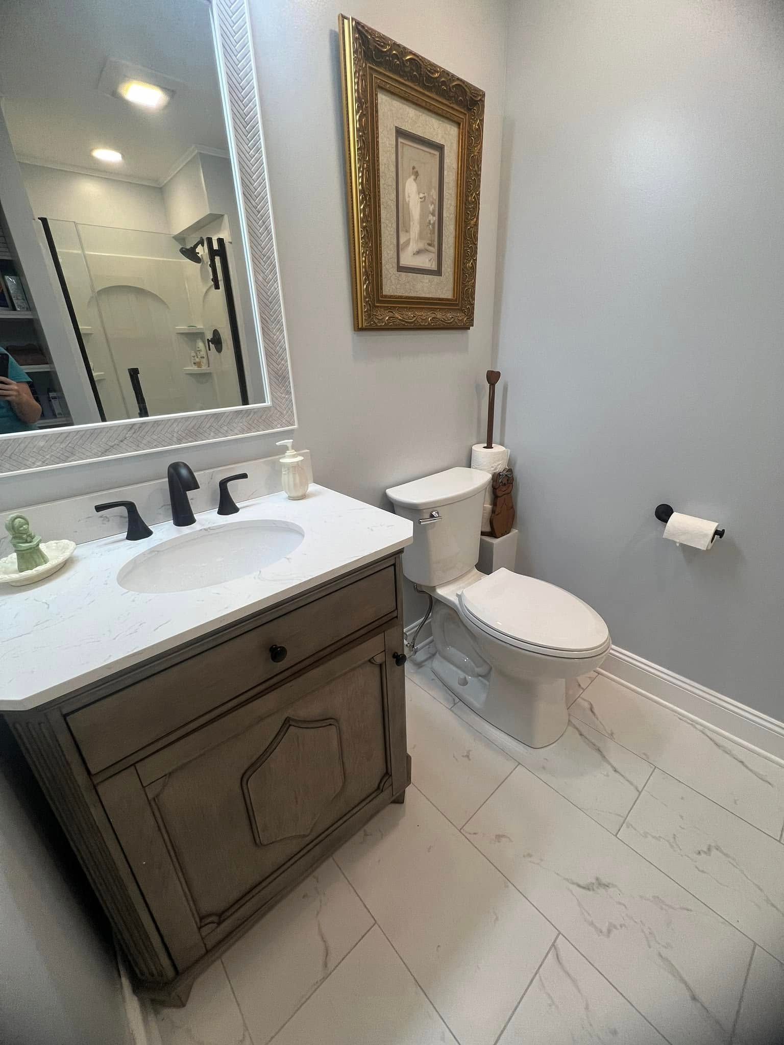 A bathroom with a sink, toilet and mirror.