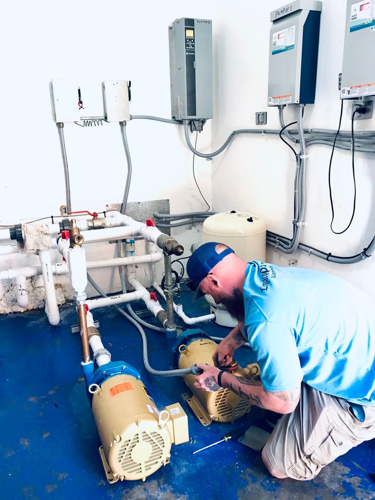 Technician kneels beside pool equipment, inspecting pipes and a motor in a utility room.