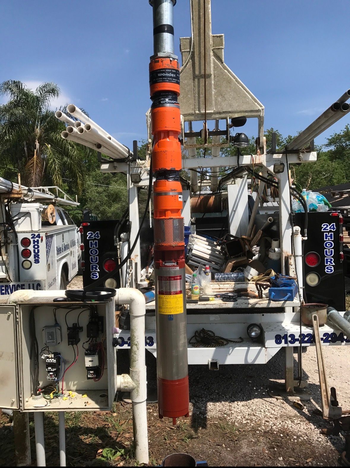 Orange utility pole with warning stickers in front of construction equipment and vehicles outdoors