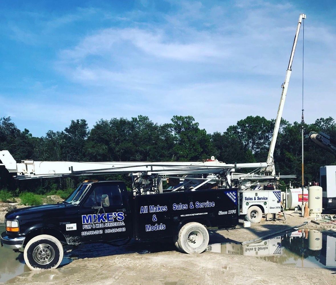 Utility trucks and a crane at a construction site under a blue sky.