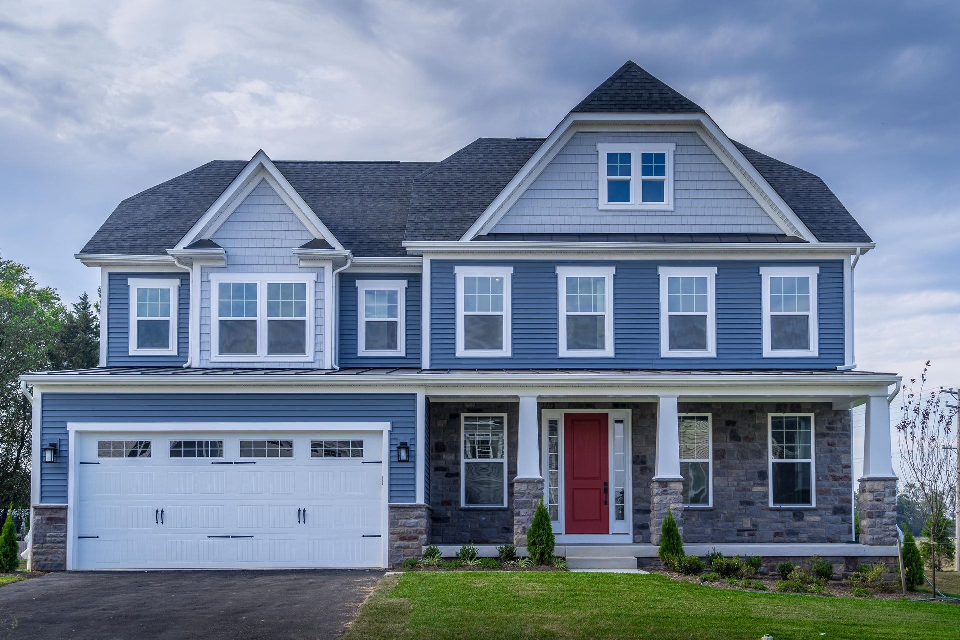 Two-story gray house with white trim, a red front door, and an attached double garage.