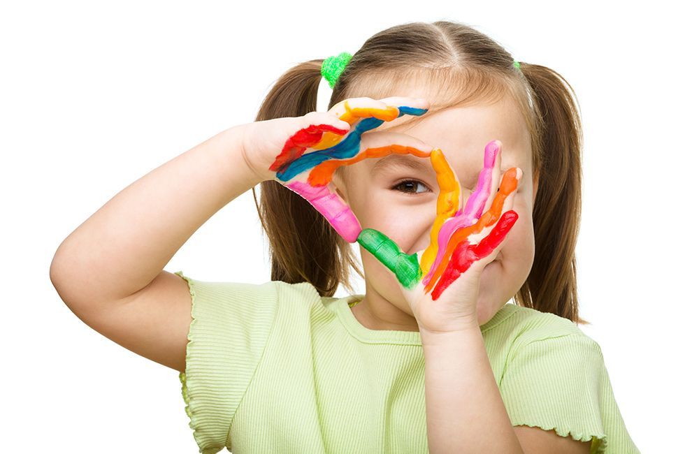 A little girl with paint on her hands making a heart shape