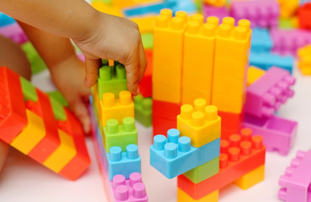 A child is playing with a bunch of colorful plastic blocks.