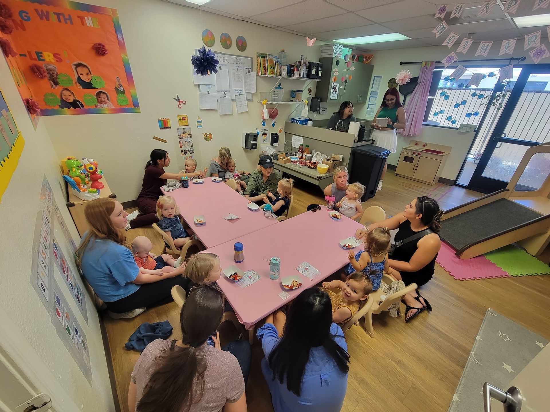 A group of people are sitting around a pink table in a room.