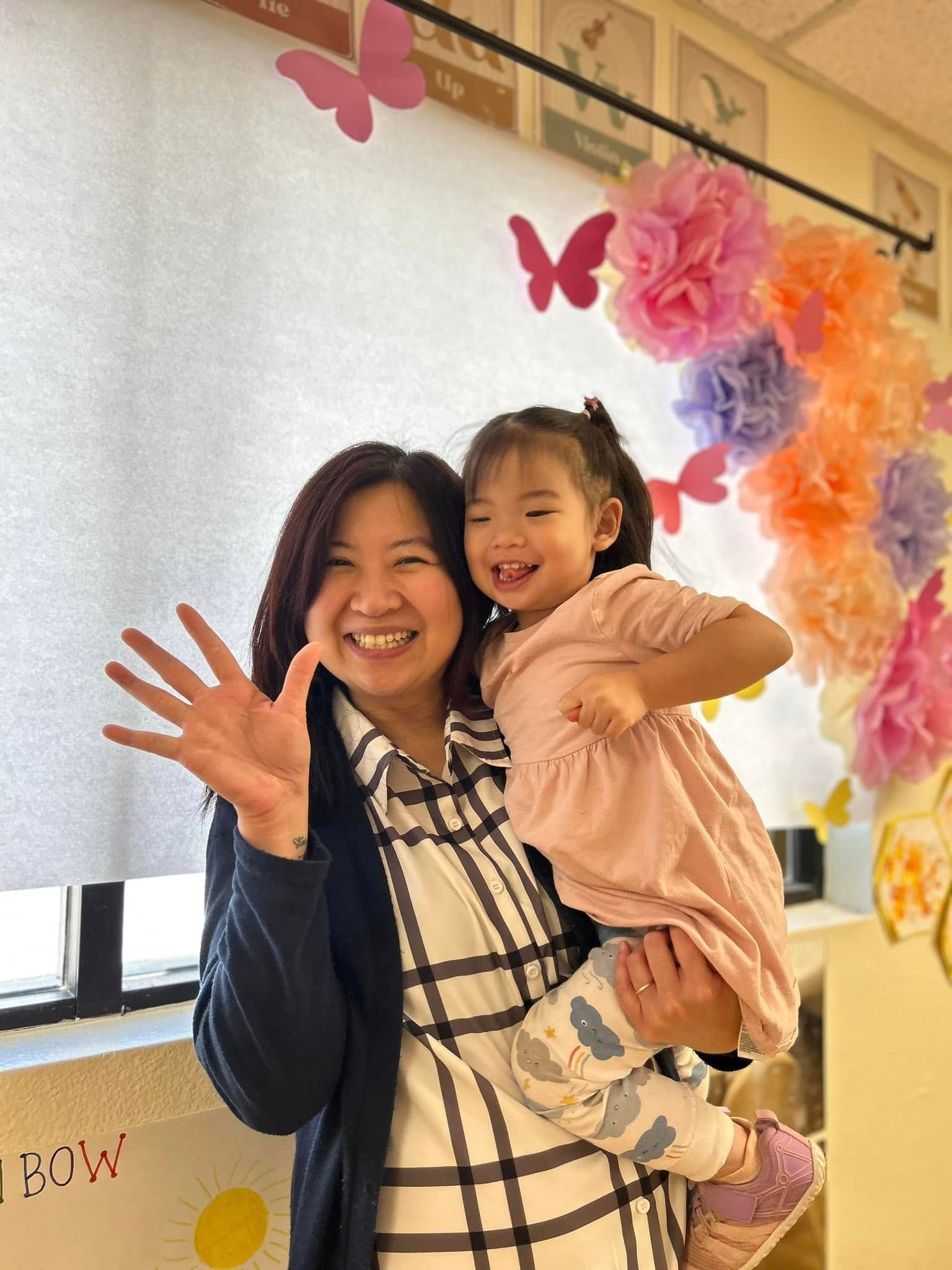 A woman is holding a little girl in her arms and smiling.