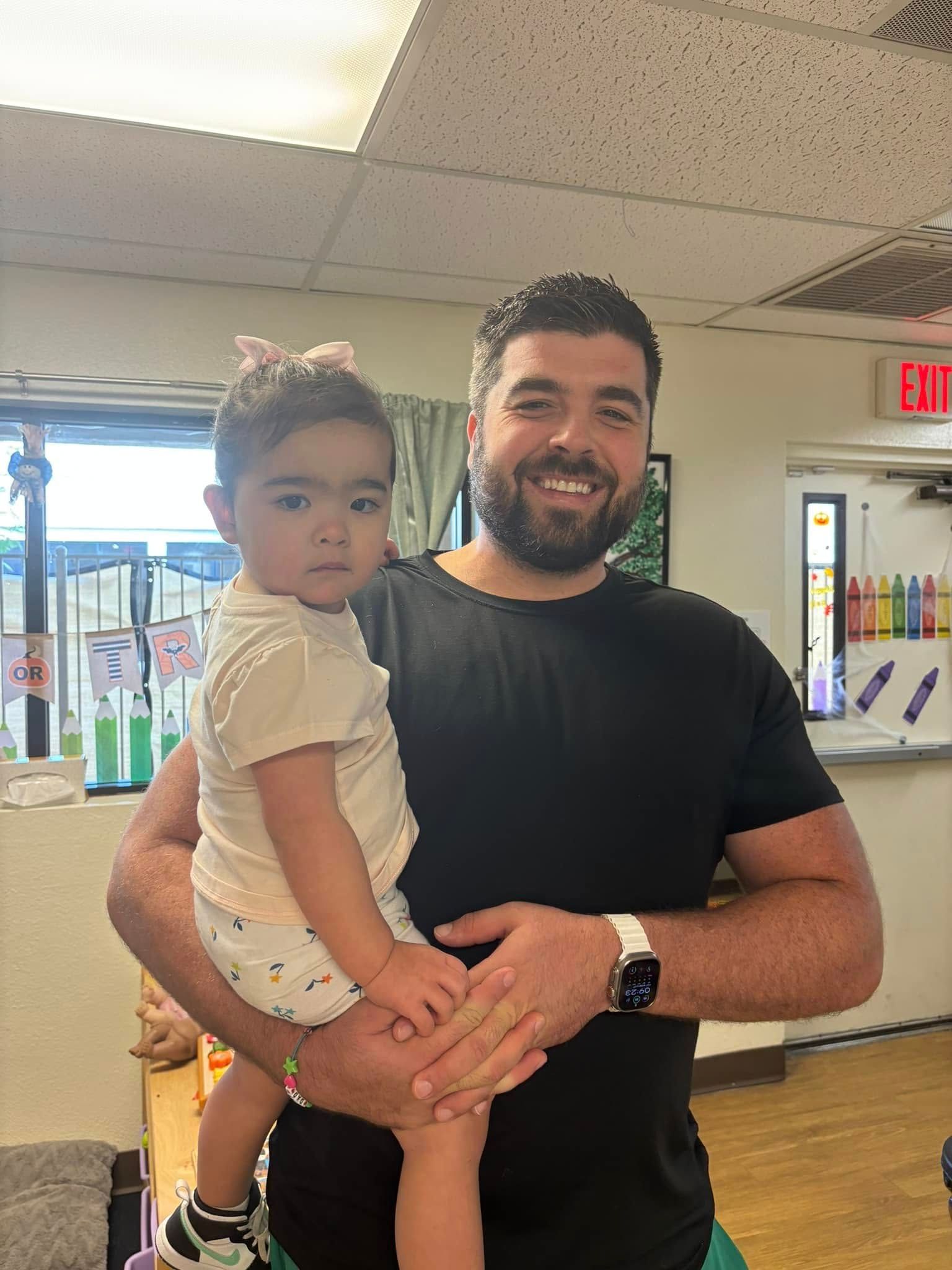 A man is holding a little girl in his arms in a room.