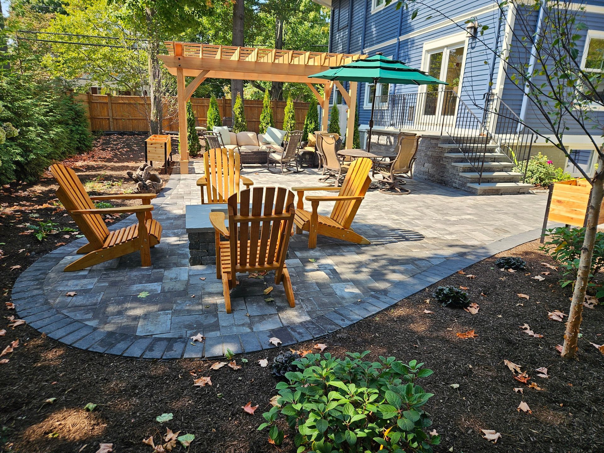 A patio with chairs , umbrellas , a fire pit and a pergola.