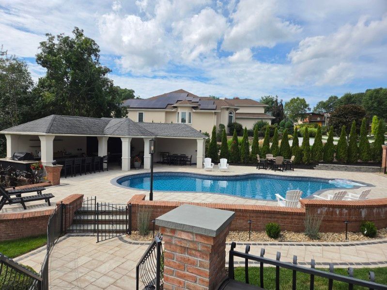 Backyard with swimming pool, gazebo, lounge chairs, and house under a partly cloudy sky