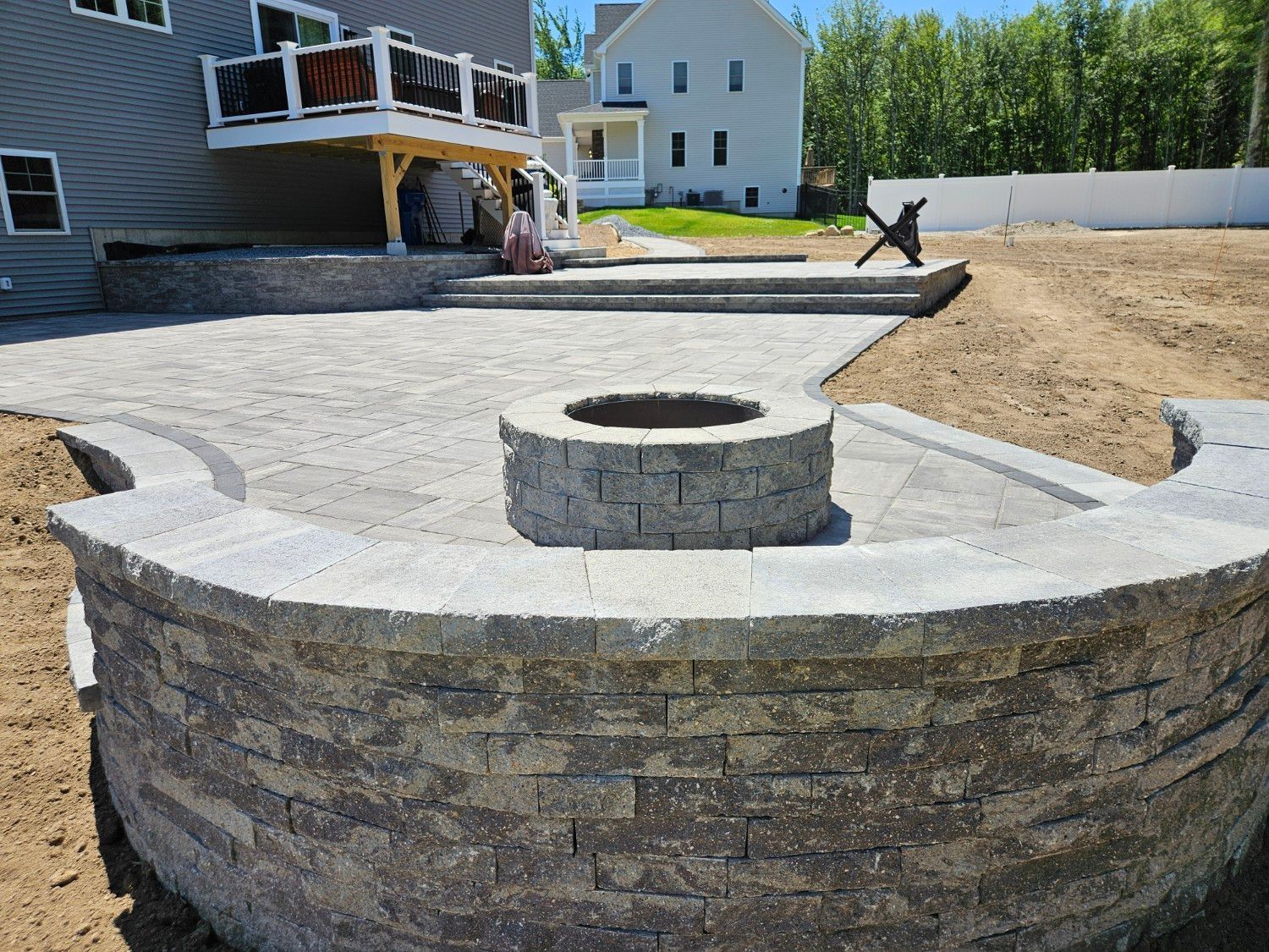 A fire pit is sitting in the middle of a patio next to a house.