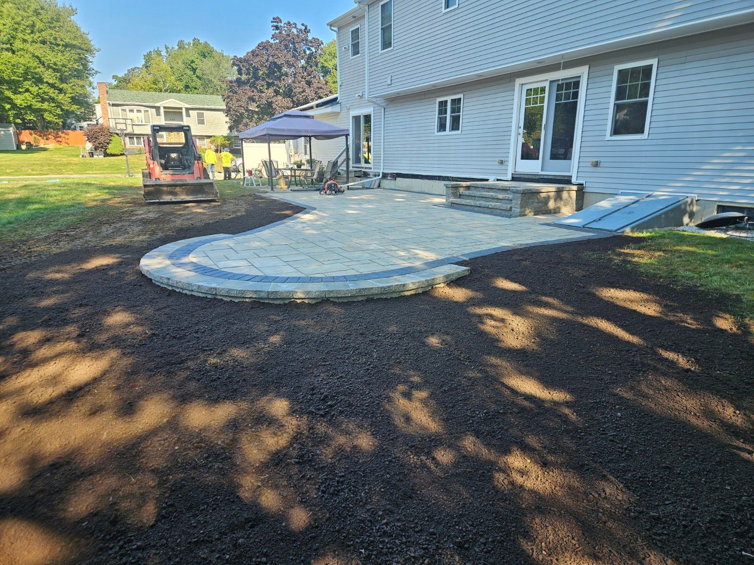 A patio is being built in the backyard of a house.