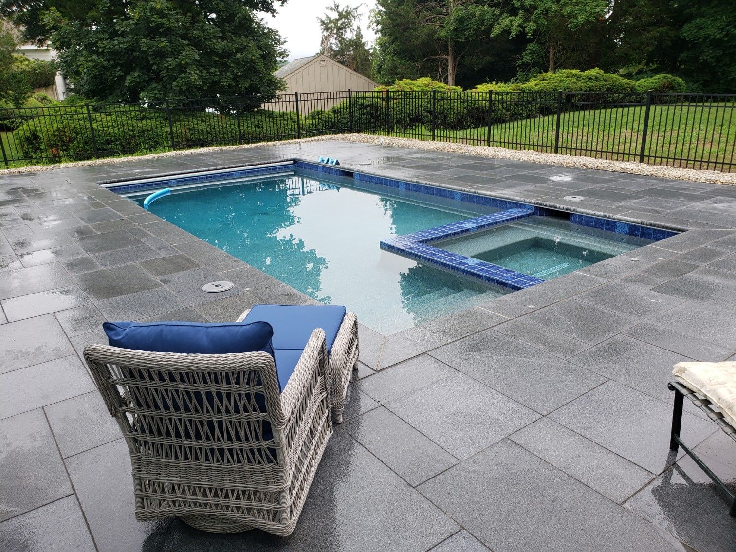 A chair is sitting next to a large swimming pool.