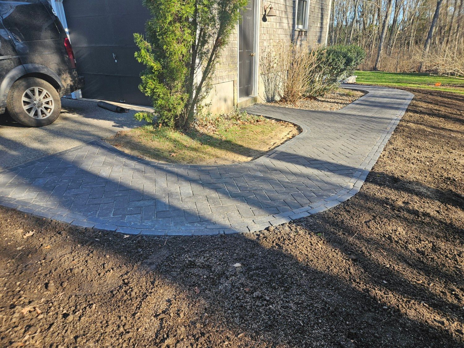 A car is parked in a driveway next to a house.