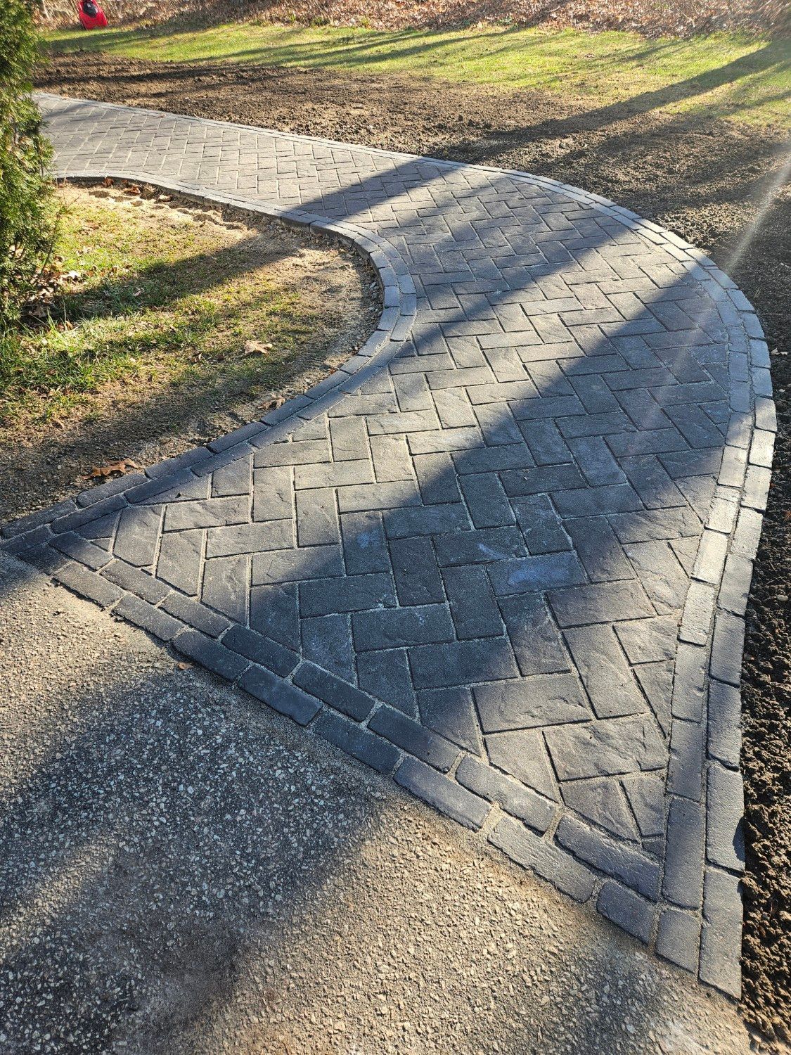 A brick walkway going through a lush green field.