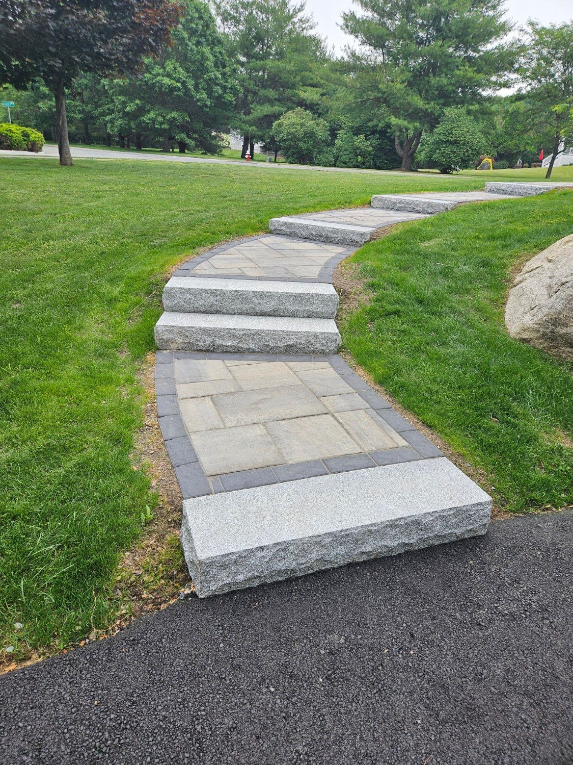 A stone walkway going through a grassy field.