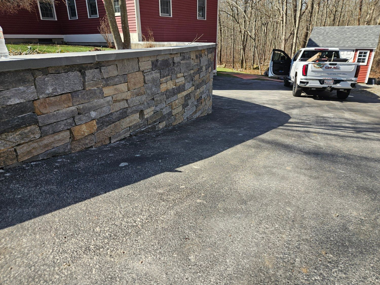 A truck is parked in a driveway next to a stone wall.