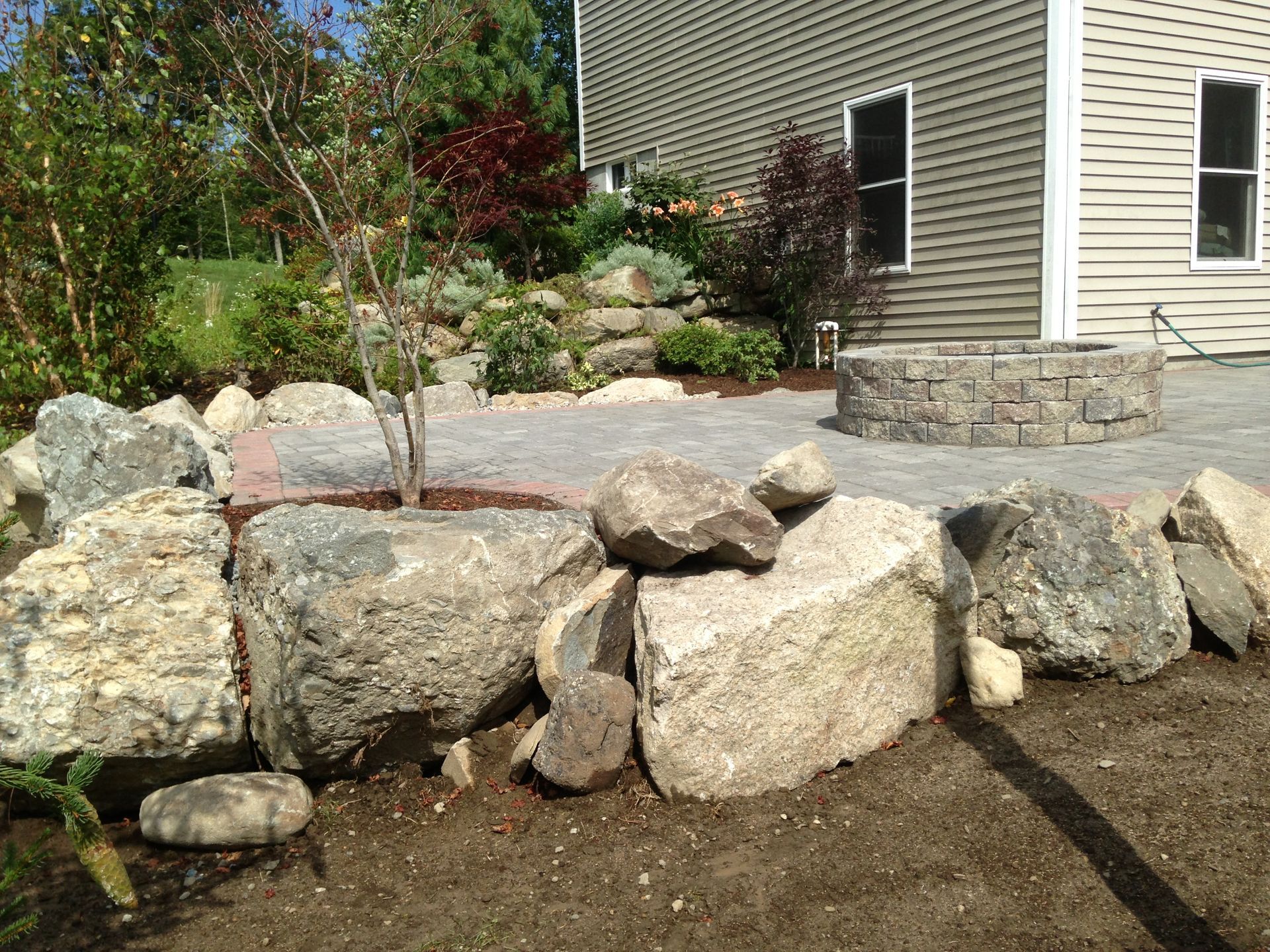 A large pile of rocks is in front of a house.