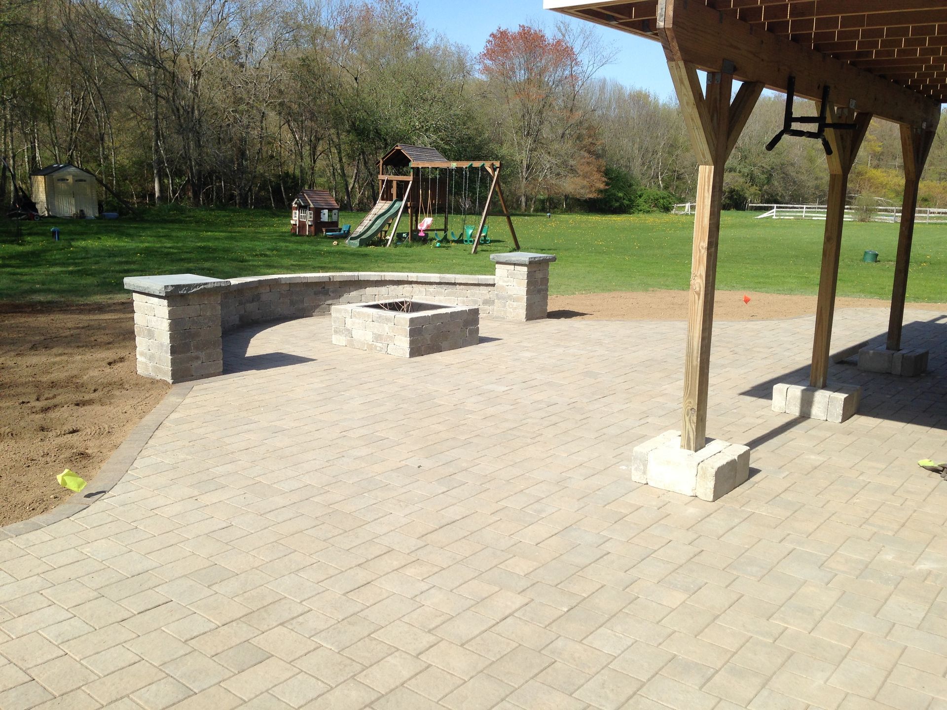 A patio with a fire pit and a playground in the background