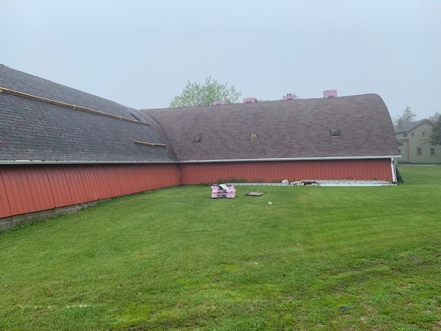 A large red barn is sitting in the middle of a lush green field.