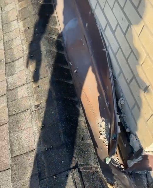 A shadow of a person is cast on a brick wall.