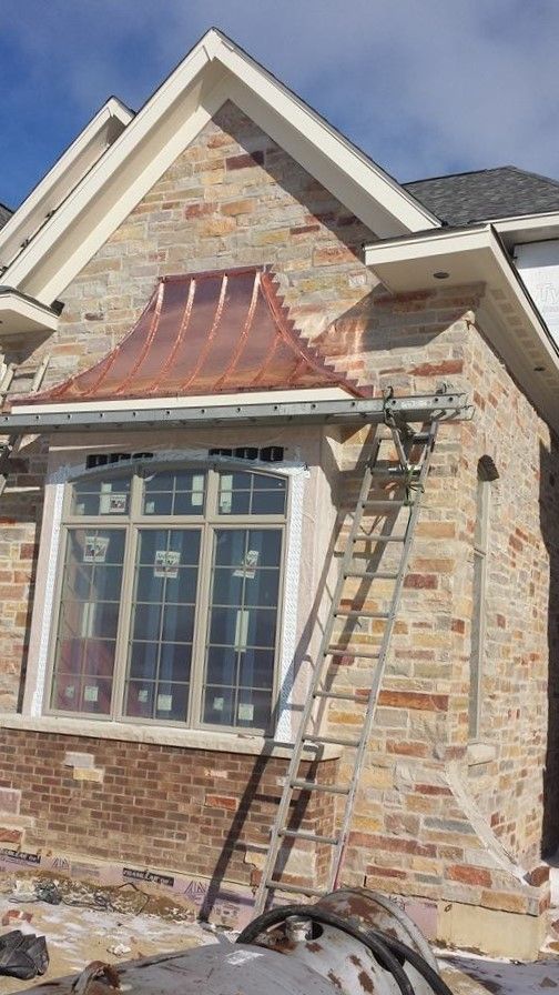 A ladder is sitting on the side of a brick house.