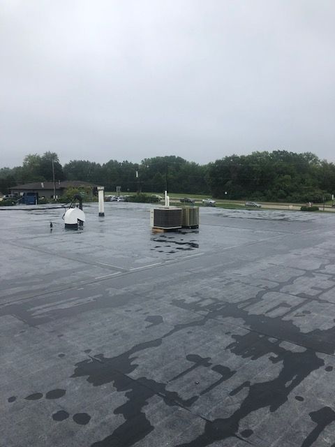 A roof with a lot of water on it and trees in the background