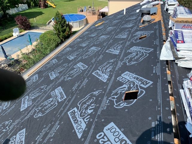 A roof with a lot of shingles on it and a pool in the background.