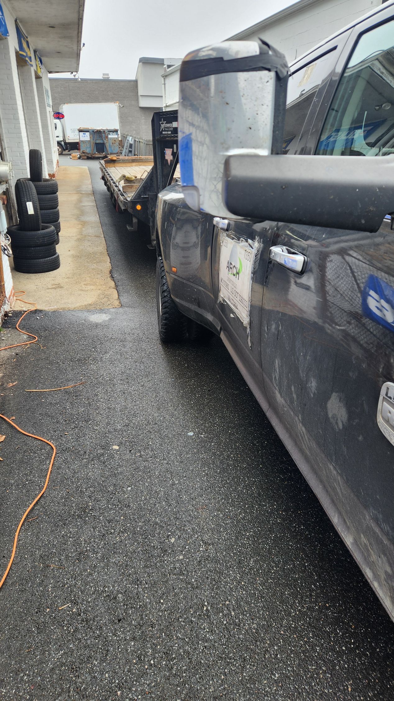 A black truck is parked on the side of the road next to a tow truck.