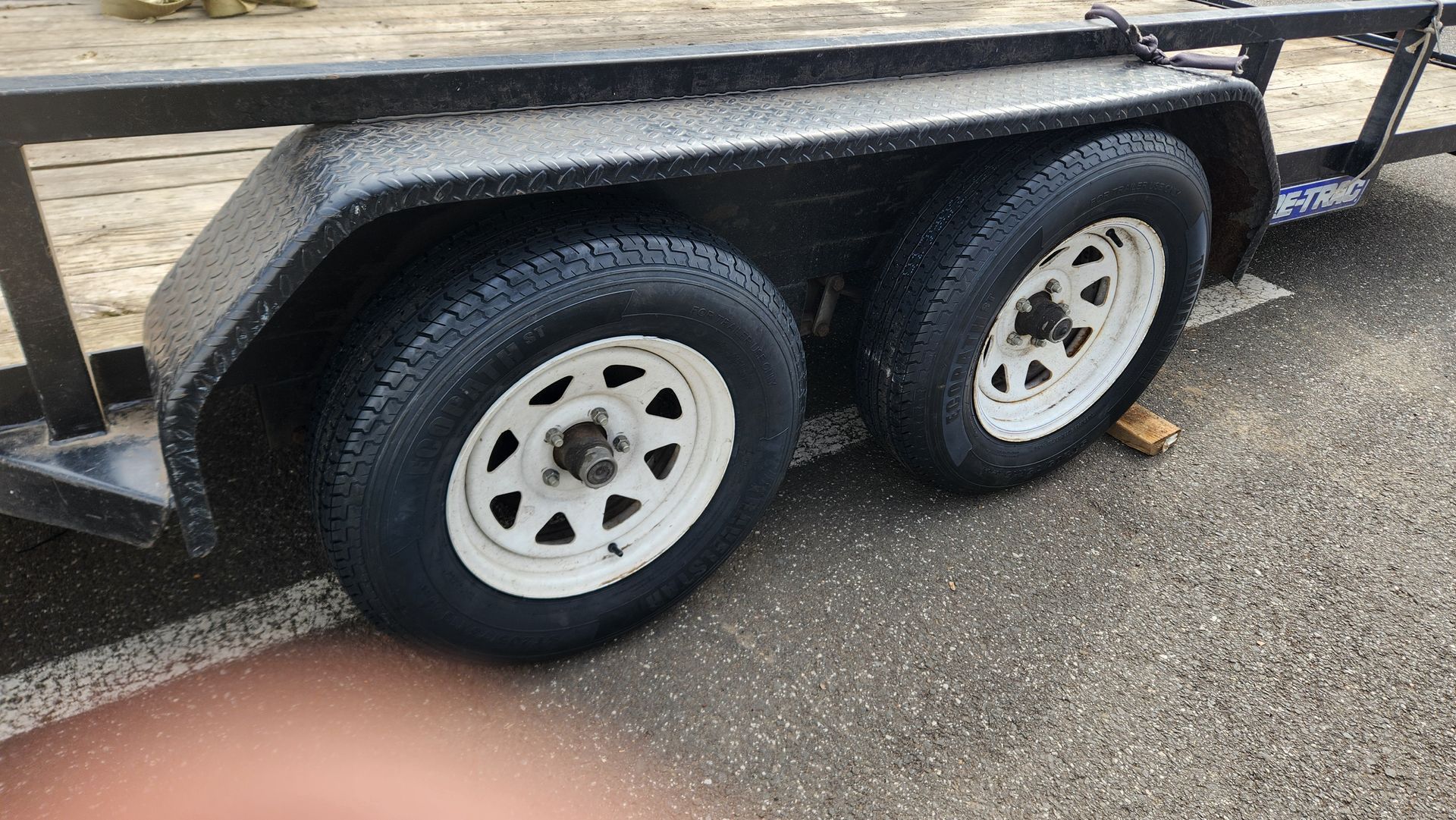 A trailer with two tires is parked on the side of the road.