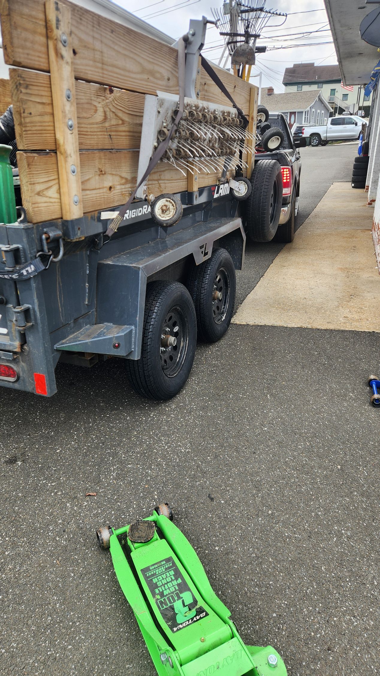 A green jack is sitting on the ground next to a trailer.